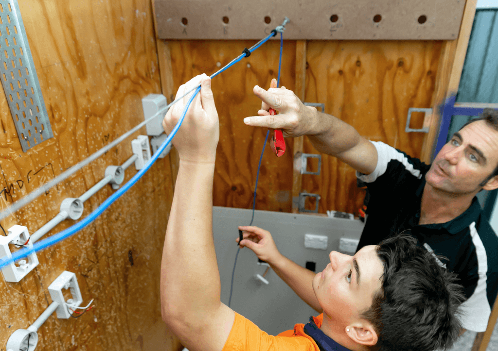 ATCNB student with trainer fixing cable overhead